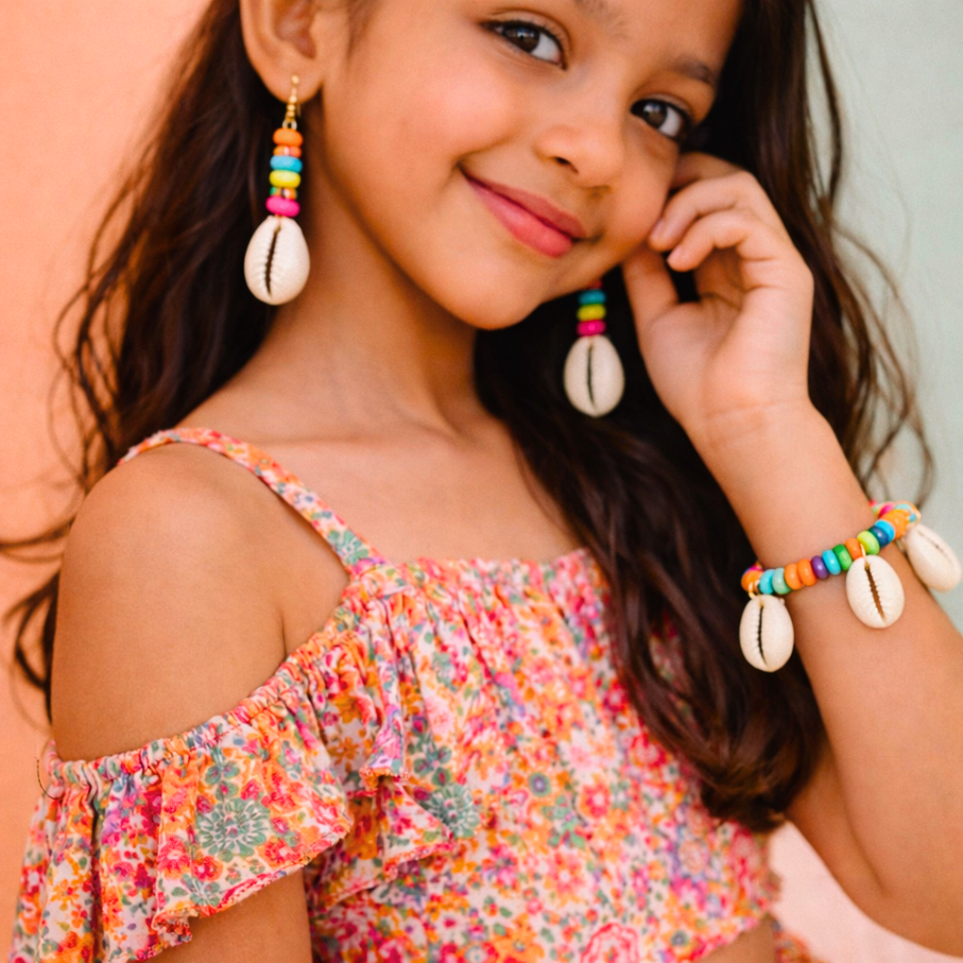 Girl wearing multicolor wooden bead bracelet with cowrie bead earrings for beach and party styling